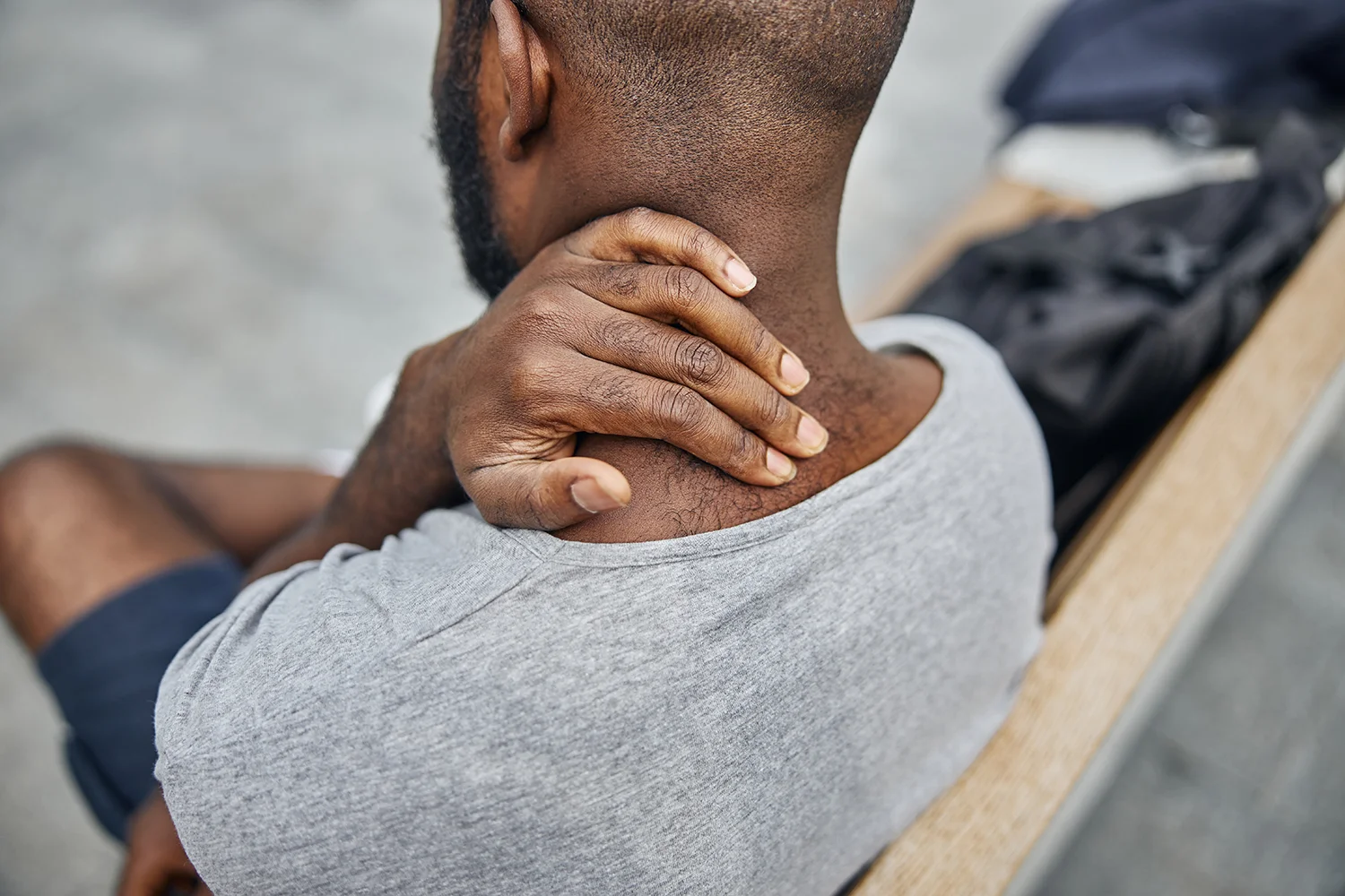 man massaging stiff neck while sitting