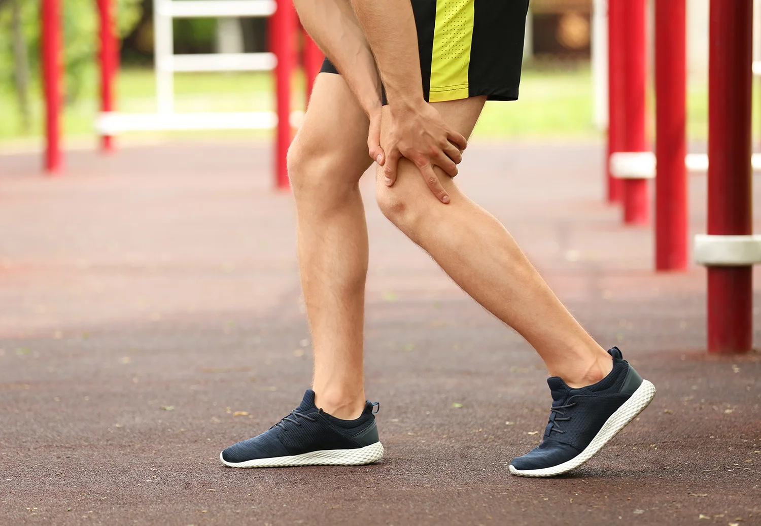 young man grips leg in pain