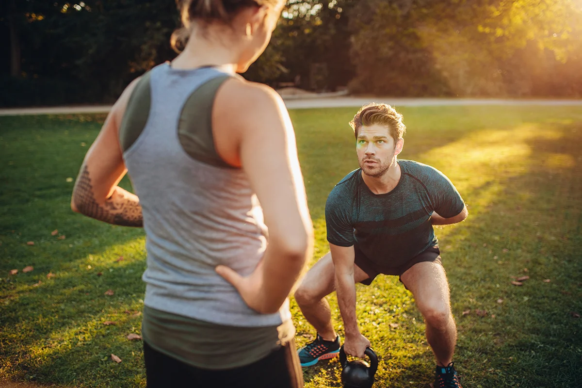 personal trainer with man doing weight training